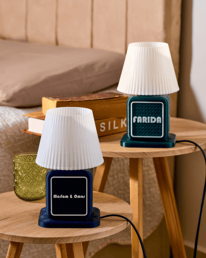 Two small retro radio lamps with white lampshades on wooden tables, one labeled 'Farida' and the other 'Marlam & Omar'.